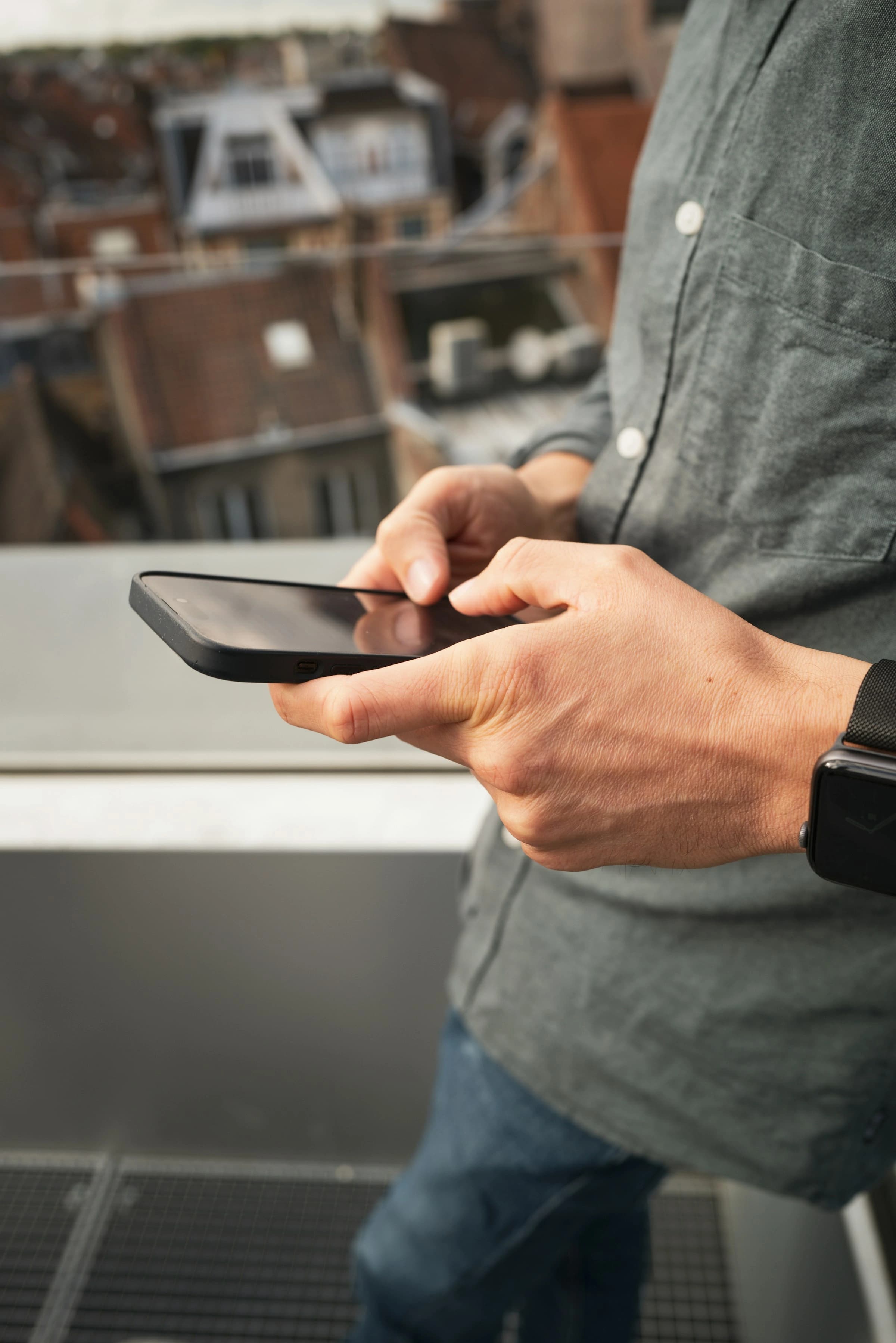 Mains tenant un smartphone au-dessus des toits d'une ville