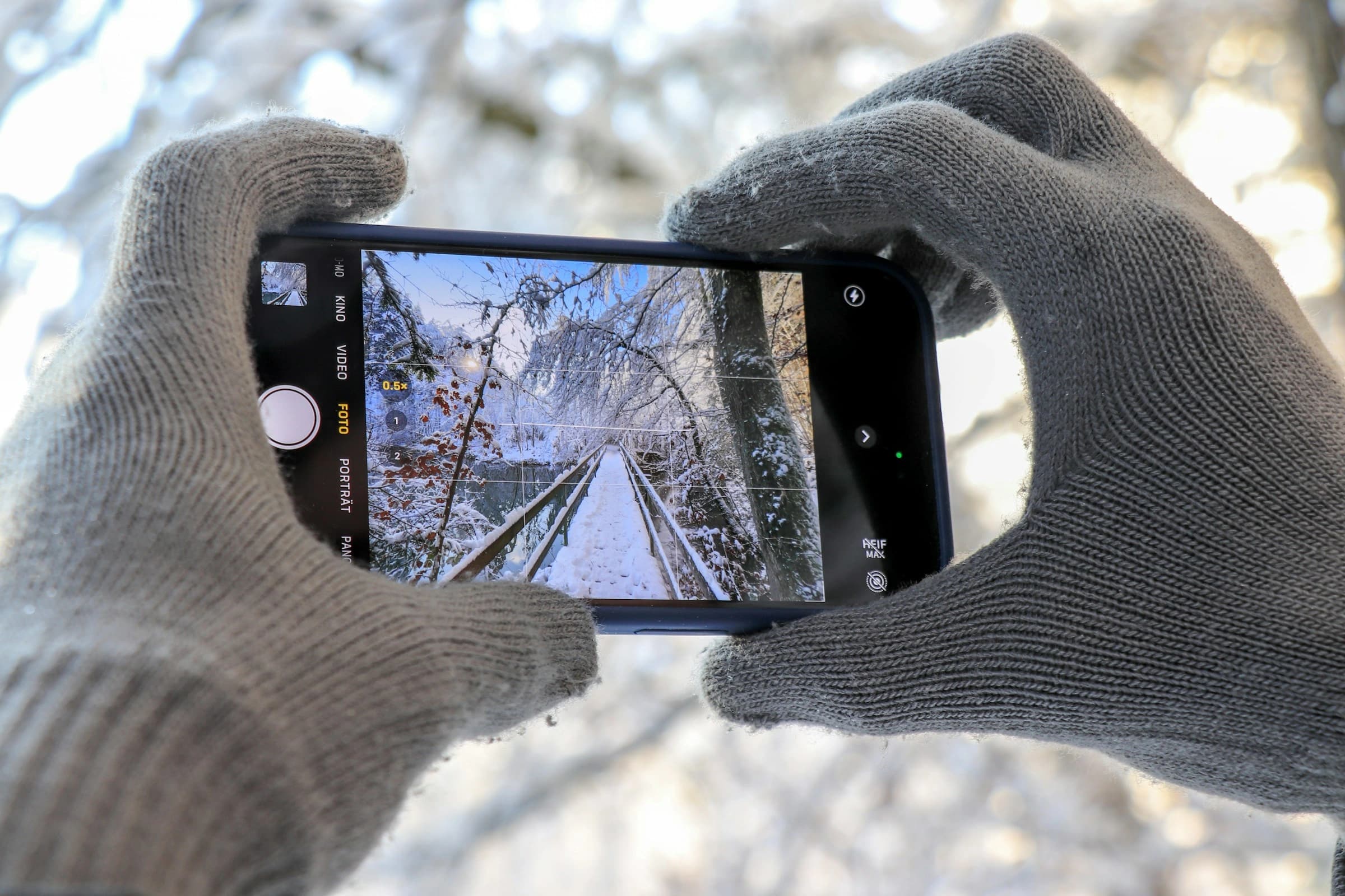 Mains gantées tenant un smartphone dehors, en hiver